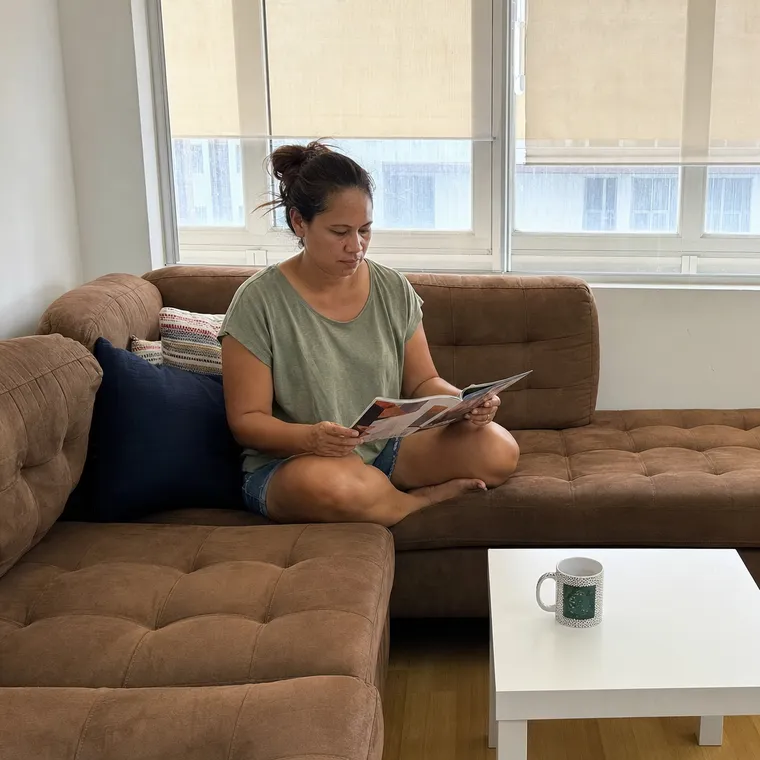 Une femme lit un magazine, assise en tailleur dans le grand canapé du salon