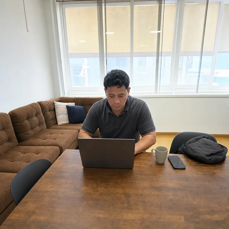 Un homme travaille sur son ordinateur portable à la grande table du salon